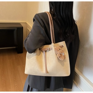 Detail view of large beige suede tote bag with brown straps and cute bear charm pendant