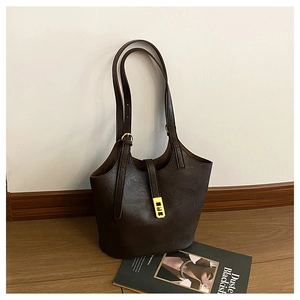 Detail of vintage brown tote bag showing slim straps and gold metal buckle accents