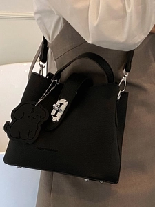 Minimalist black lychee leather bucket bag with silver lock and dog charm on a model