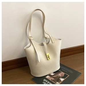 Close-up of minimalist cream white bucket bag with elegant golden vertical metal buckle