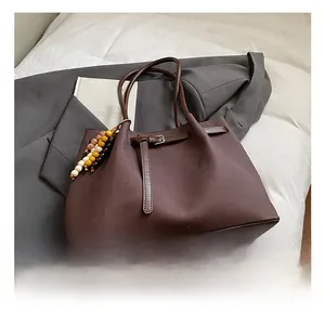 Detailed view of brown textured tote bag with ethnic bead charm on a grey suit jacket