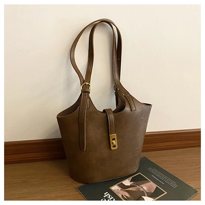 Detail of dark brown tote bag with vintage gold twist lock and glossy oil-wax leather texture