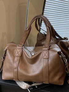 Brown vintage Boston travel bag with woven strap and large capacity on dark surface
