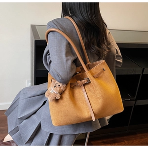 Detail of tan suede tote bag with leather straps and cute plush bear charm decoration