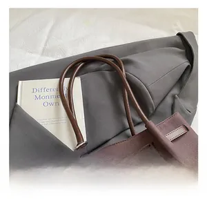 Close-up of deep brown canvas tote bag with round leather handles and ethnic beaded charm