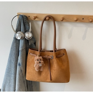 Detail of vintage brown suede tote bag with metal buckle and cute plush dog pendant