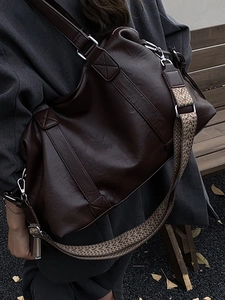 Retro brown large tote bag with a vintage patterned wide strap on a wooden bench