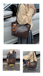 Close-up of vintage brown tote bag texture with cute bear charm and embossed logo detail