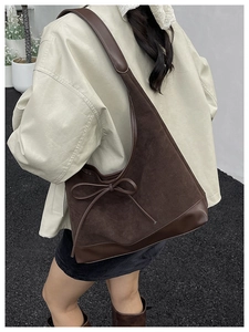 Brown suede patchwork tote bag with bow detail worn by a model in an outdoor setting