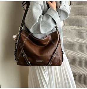 Detail of vintage brown leather tote bag showing white stitching and silver buckles