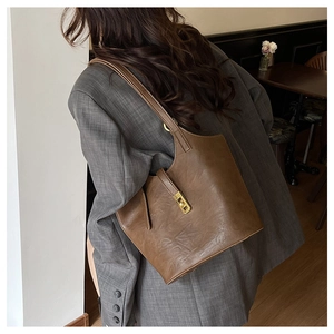 Detail of vintage brown leather tote bag showing golden twist lock and smooth texture