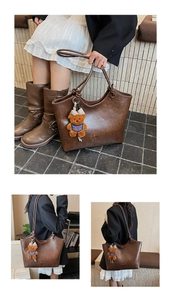 Detail of dark brown leather tote bag with embossed logo and a cute brown bear charm