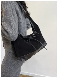 Close-up of black matte tote bag featuring stylish ribbon bow and patchwork leather details