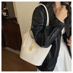 Detail view of cream white leather tote bag with elegant gold metal twist-lock buckle