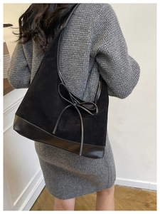 Detail of black suede hobo bag featuring leather patchwork and stylish bow decoration