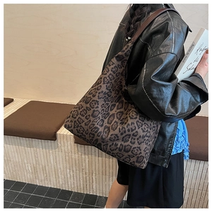 Detailed view of the large leopard print suede tote bag worn on shoulder by a model