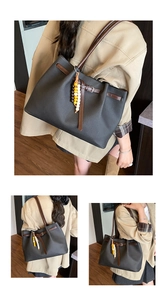 Detail of vintage black tote bag with brown leather straps and colorful beaded charm