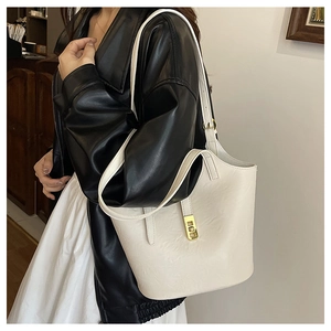 Close-up of ivory minimalist tote bag with gold buckle on a stylish model in leather jacket