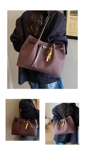 Detail view of brown tote bag with decorative leather strap and retro beaded charm