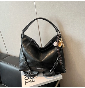 Detail of black glossy tote bag with white contrast stitching and baseball themed keychain
