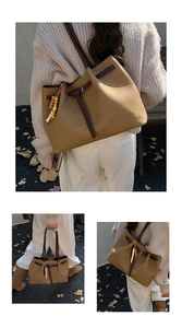Detail of khaki canvas tote bag with brown leather straps and colorful beaded charm