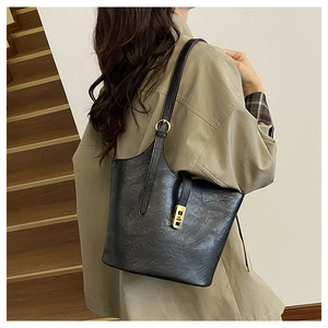 Detail of a vintage black leather tote bag with elegant gold metal clasp and soft texture
