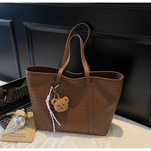 Détail de la texture d'un sac cabas tressé avec ours en peluche et foulard en soie rayé
