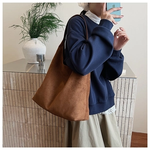 Close-up of a large brown suede tote bag worn by a model for a relaxed commute style
