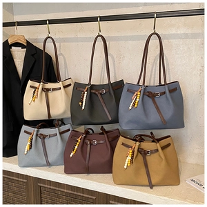 Detail view of large tote bags in six colors with decorative beaded charms and brown handles