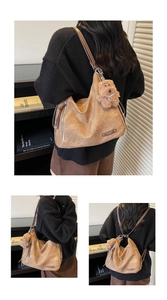Detailed view of brown soft leather tote bag with vintage texture and plush dog pendant