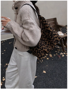 Close-up of a large leopard print tote bag with leather strap in an outdoor autumn setting