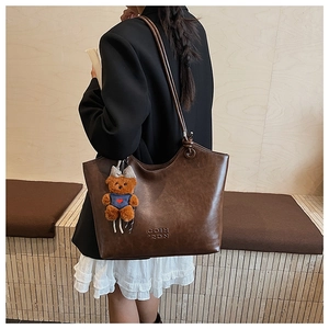 Detail of vintage brown tote bag with leather texture and bear plush charm