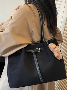 Retro black suede tote bag with leather buckle straps and plush bear charm on model