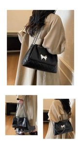 Close-up of black quilted leather tote bag with silver butterfly metal buckle detail