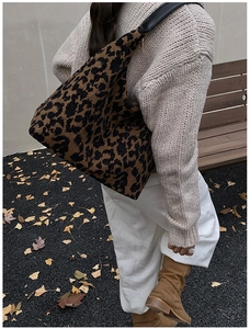 Detail of leopard print tweed tote bag with black leather handle in autumn setting