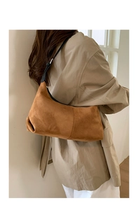 Detail of soft brown suede hobo bag with adjustable black strap and silver buckle