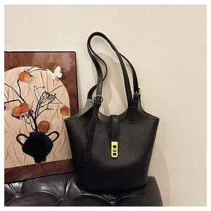 Detail view of black lychee-textured bucket bag with premium gold metal lock and strap
