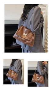 Detail of brown quilted faux leather tote with silver butterfly buckle and chain strap