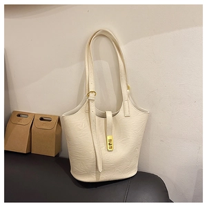 Detailed view of cream-colored pleated leather bucket bag with gold metal buckle