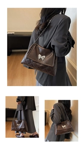 Detail of vintage brown quilted crossbody bag with silver butterfly buckle and chain strap