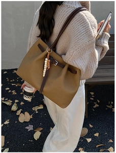 Brown faux leather tote bag with ethnic bead charm shown in an urban commute setting