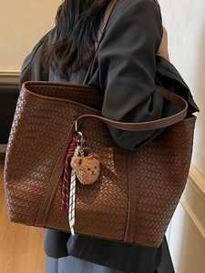 Grand sac fourre-tout tissé marron foncé porté à l'épaule par un mannequin en style chic