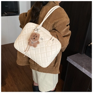Detail of cream quilted tote bag with brown bear charm and classic diamond pattern texture