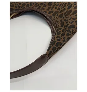 Detail of reinforced handle stitching and leopard print canvas texture on tote bag