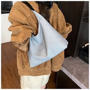 Detail of light blue hobo tote bag with black leather strap worn by a female model