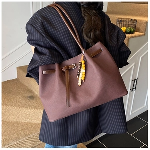 Detail of vintage brown canvas tote bag with leather straps and ethnic tassel charm