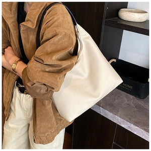 Close-up of beige canvas hobo tote with premium black leather strap and gold zipper detail