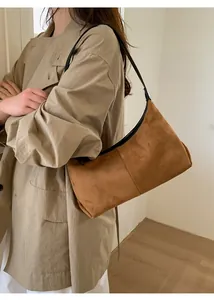 Brown suede hobo bag shown on shoulder in a minimalist indoor setting for daily wear