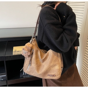 Brown faux leather hobo tote bag with shoulder strap and plush puppy charm detail