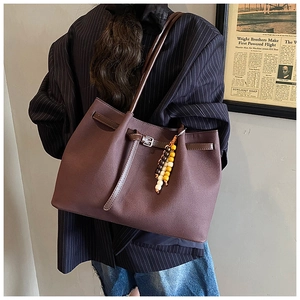 Close-up of retro brown faux leather tote with metal buckle and wood bead charm